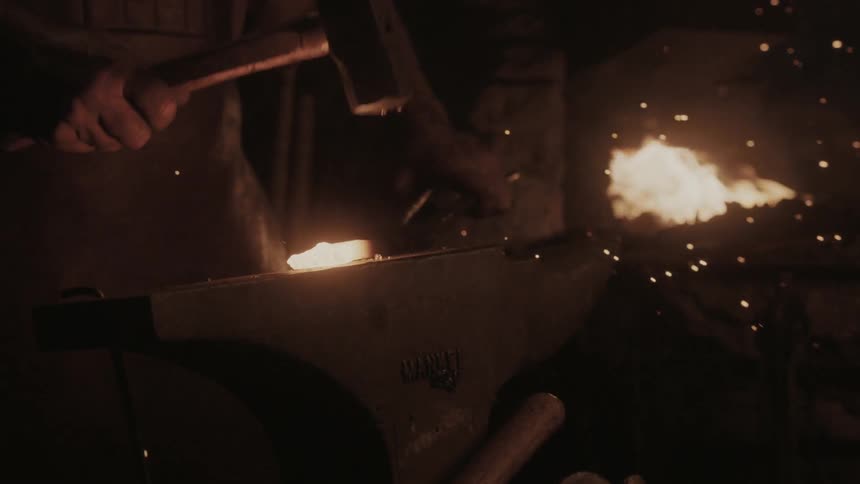 A blacksmith hammers metal on an anvil