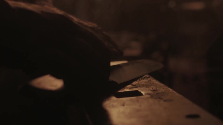 A person puts a knife down on an anvil