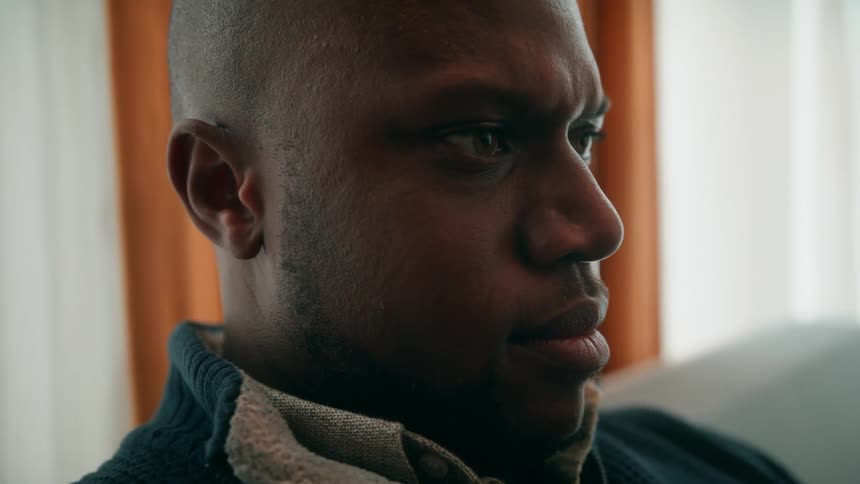 An upset looking man sitting on a sofa indoors