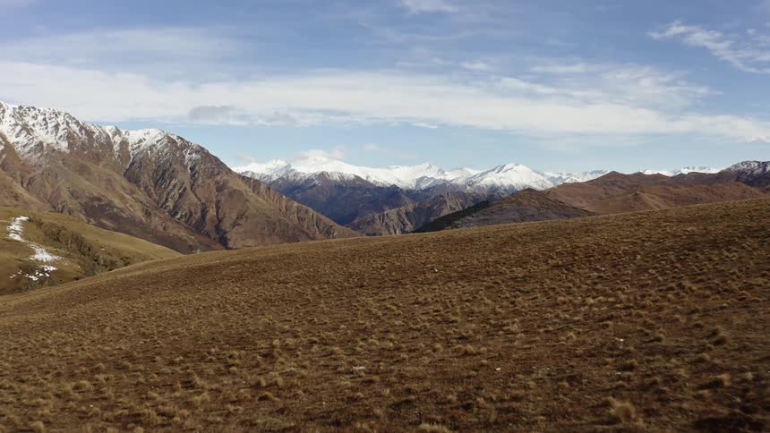 Brown hills and snow dusted mountains during spring thaw and melting