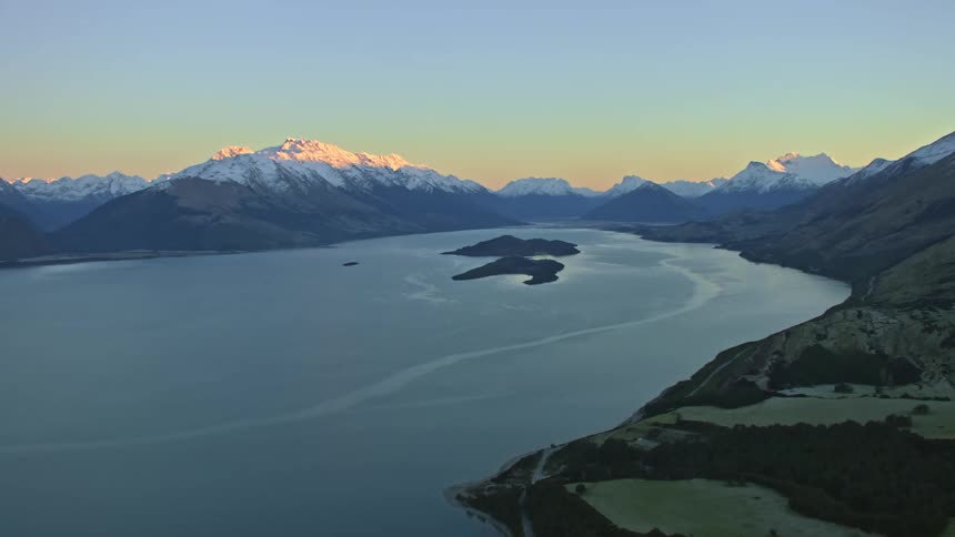 Mountain ridges with snow capped peaks around a smooth lake