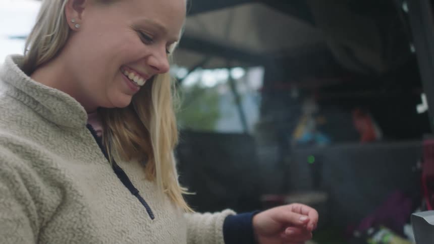 A woman is barbecuing kebabs by the tent