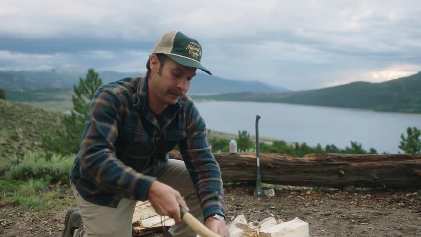 A man is chopping wood by the campfire
