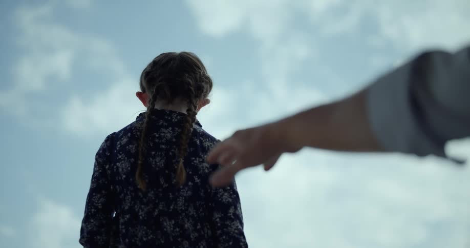 A girl turns from a reaching hand
