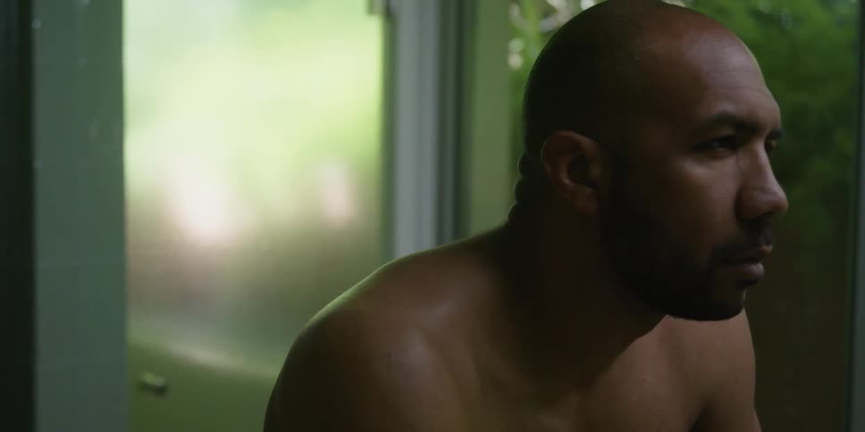 Barechested man bends slightly while thinking before straightening