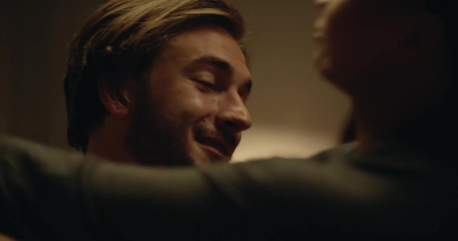 Young couple sitting on a bed talk to each other before a playful loving hug