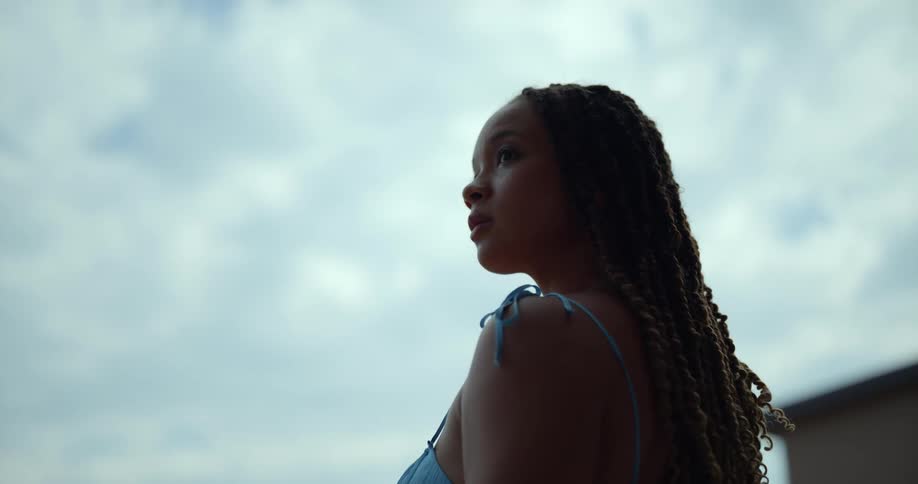 A woman with long dreadlocks standing outside on a cloudy day