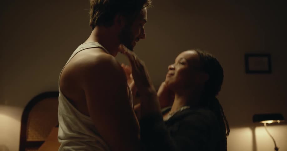 Young couple sitting in the bed hold hands and passionately kiss before laying down