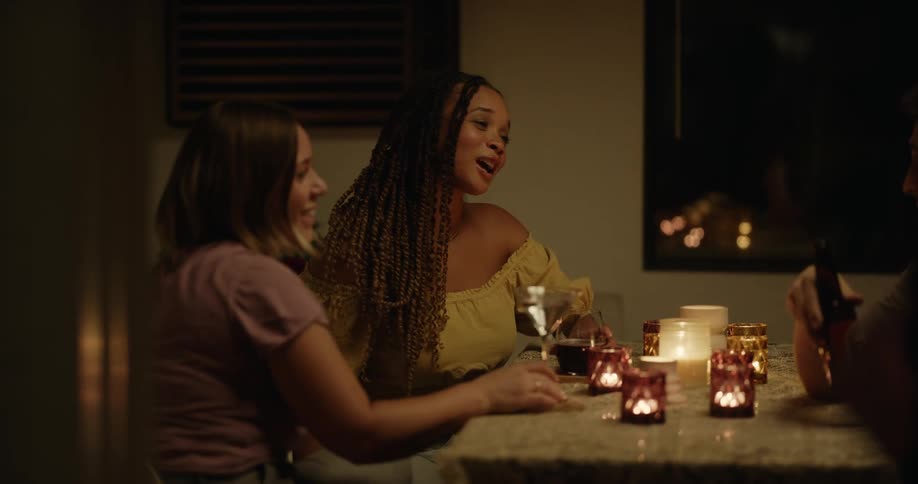 Group of young happy friends talking and drinking on a restaurant at candle light