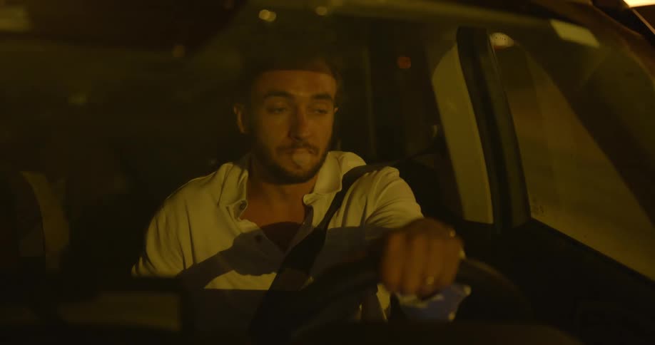 A man holds the steering wheel of his automobile as he drives at night