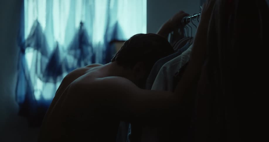 A man looks through his clothes and leans forward upset