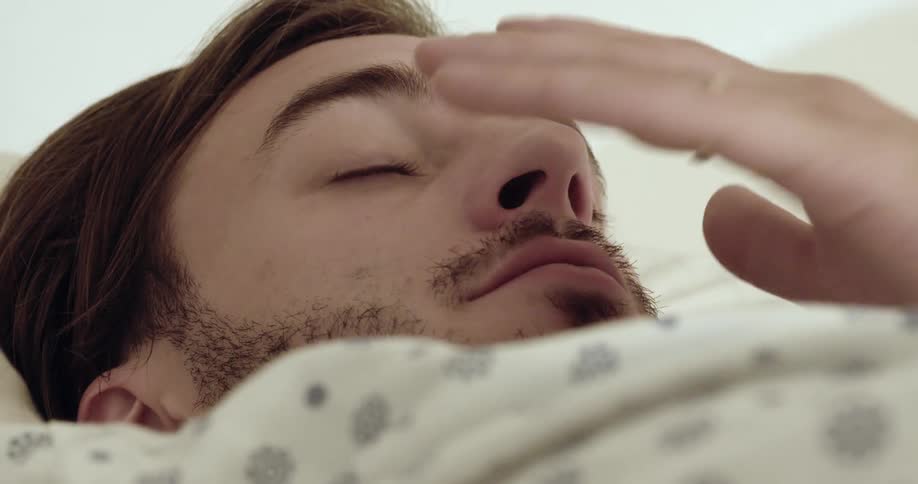 A man rubbing his eyes and face while walking up