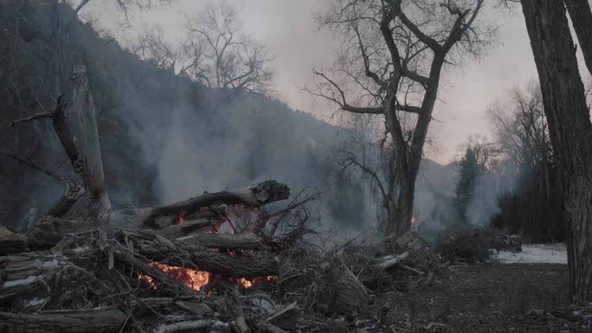 A campfire is smoking at sunset