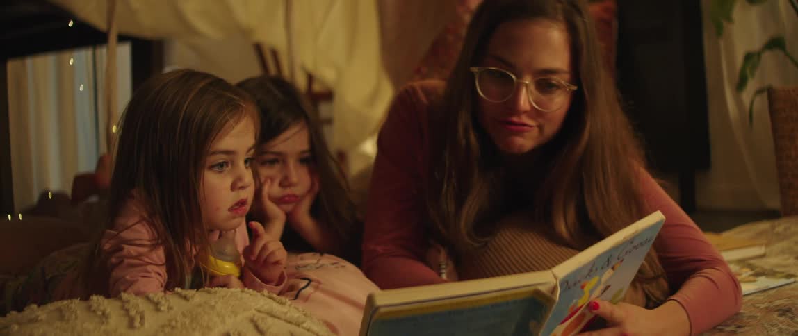 A woman reads to her daughters inside a tent