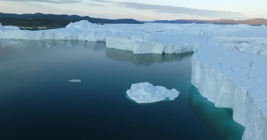 Aerial view of a glacier meeting with the ocean under a deep blue sky