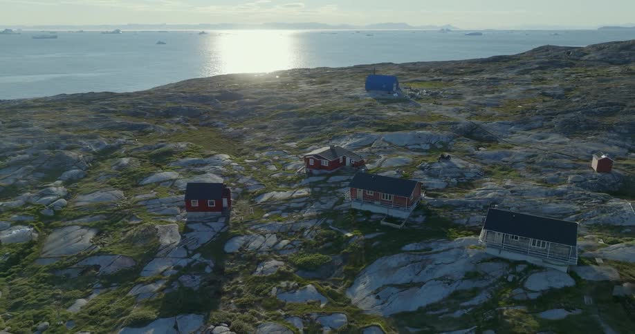 Aerial view of a scattered group of houses on the countryside next to the ocean at morning