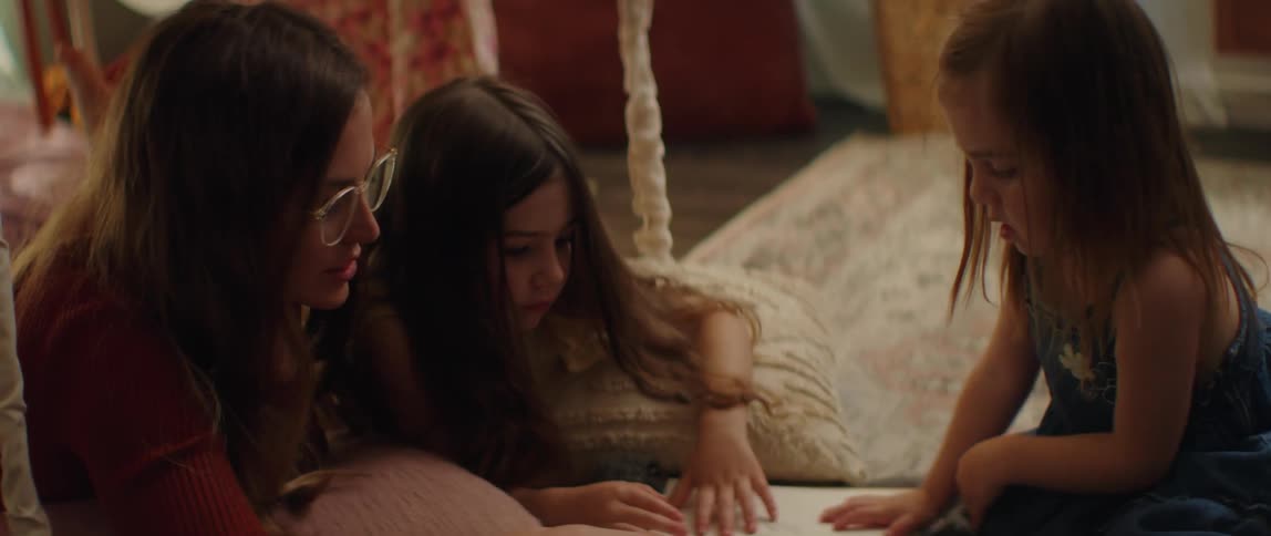 Mother and daughters read book while sitting on floor