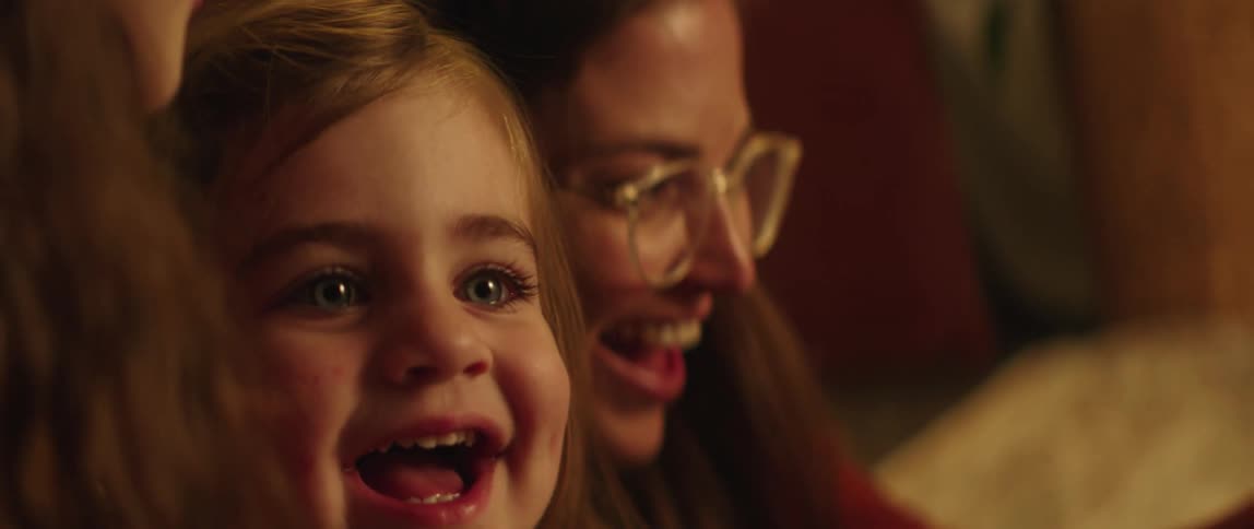 A little girl smiles and laughs at the video of her and her sister on the phone screen