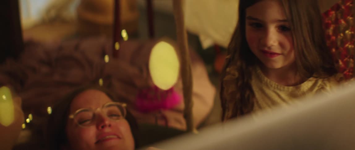 Father mother and daughters lie down on bed watching laptop in bedroom laughing