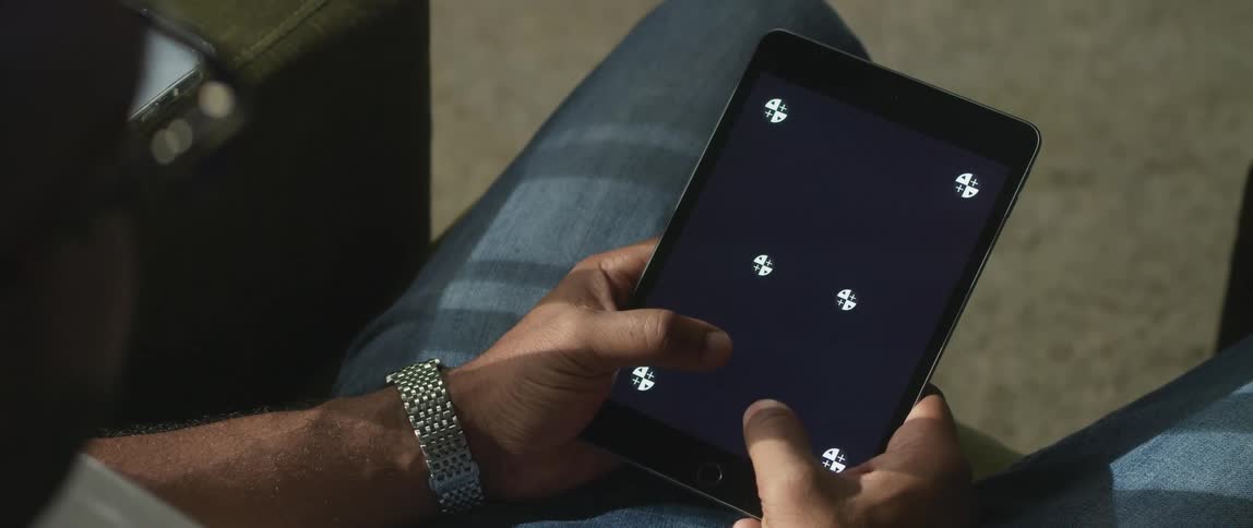 A man sends texts on a tablet while sitting on a couch
