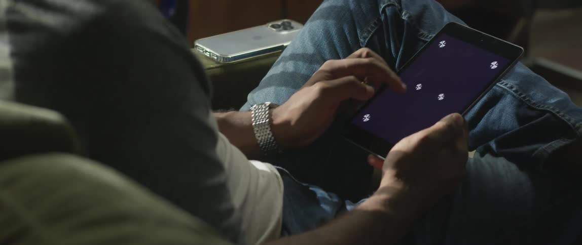 A man sitting with one leg crossed over the other scrolling on a tablet