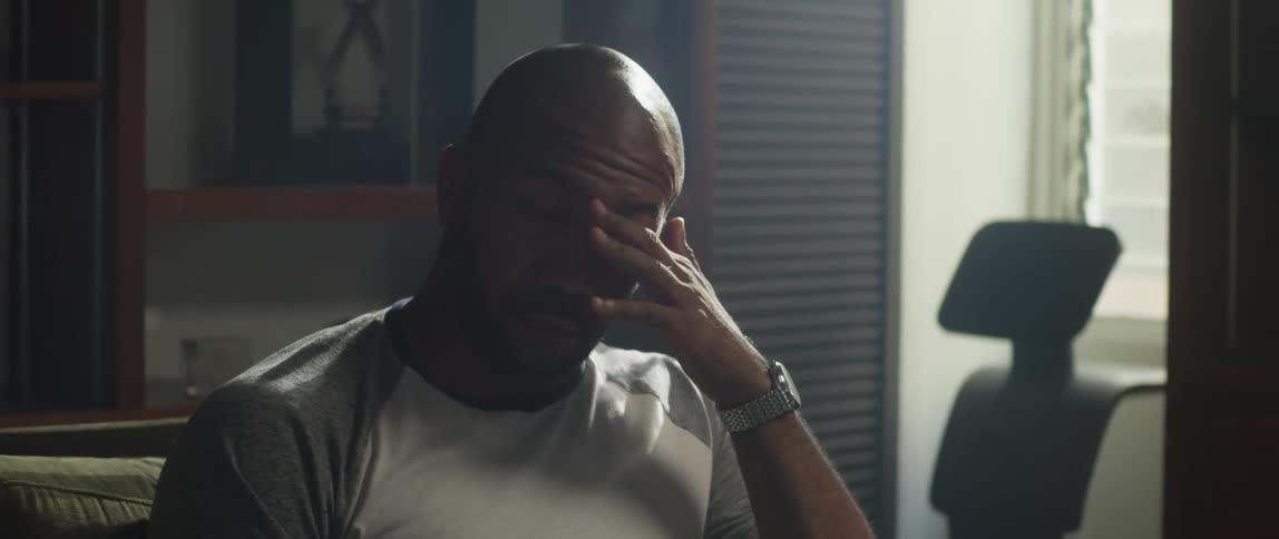A man takes off his glasses rubs his eyes and sighs deeply before checking his watch