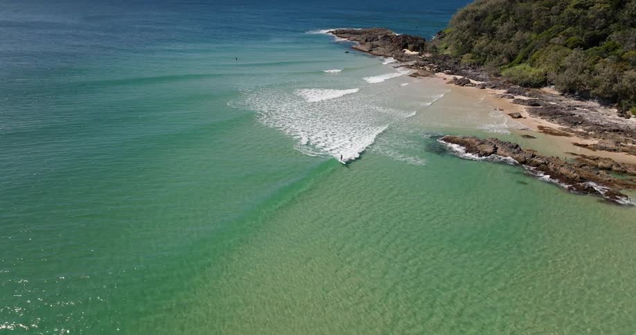 Aerial view of surfer riding ocean wave on surfboard in the bay