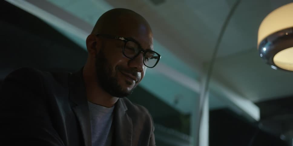 A man smiles as he looks down while working at night