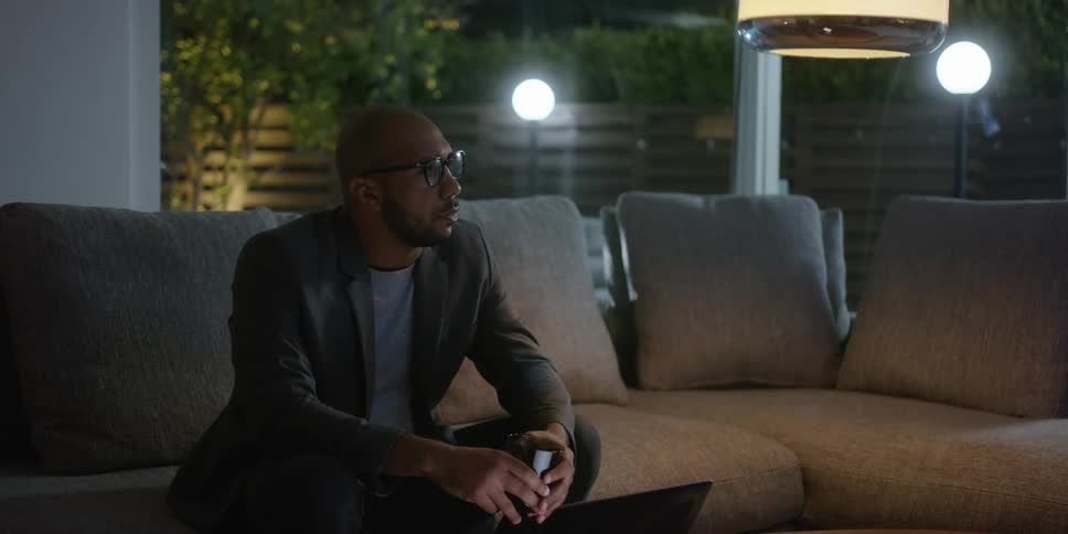 A man is sitting on a couch and drinking a beverage