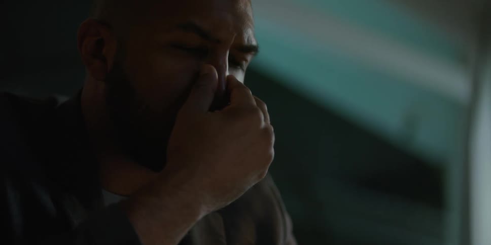 A tired looking man removing his glasses and rubbing his eyes