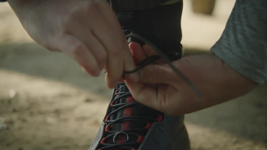 Hands lace up and tie a boot outside