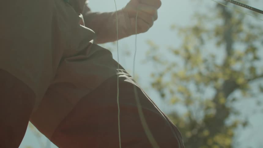 A person pulling fishing line on a fly fishing rod