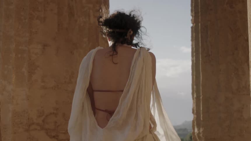 A woman wearing white robes stretches her arms out
