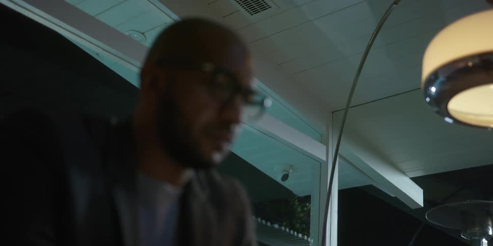 A man is sitting indoors during the night time