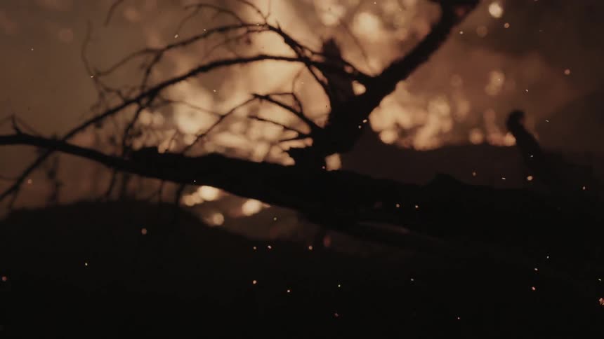 Sparks fly from a fire on a field at night