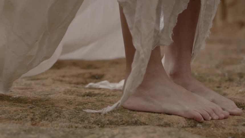 The fabric of a garment flutters near someone's feet