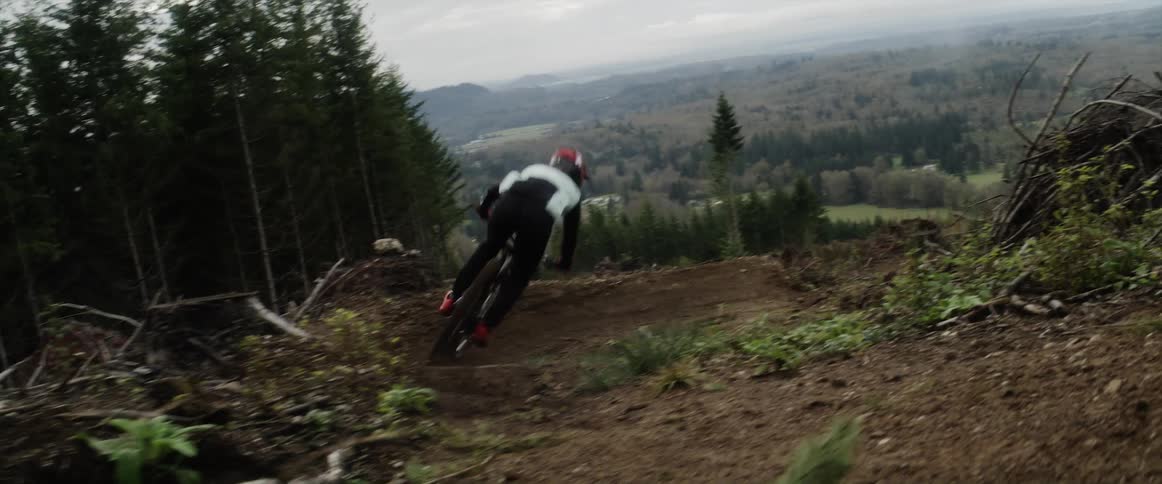 A mountain biker speeding down a dirt track on a hillside