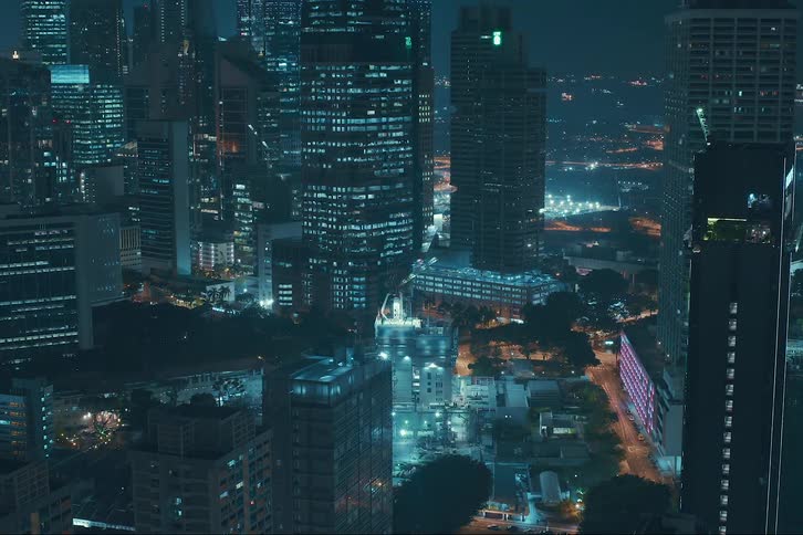 A skyscraper being constructed from the bottom up in a metropolis at night