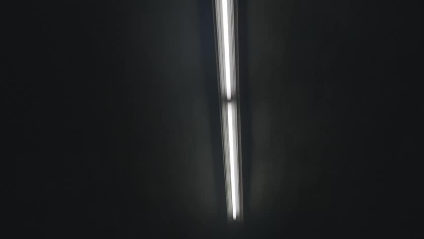 Walking under fluorescent lamps on the roof of a dimly lit tunnel