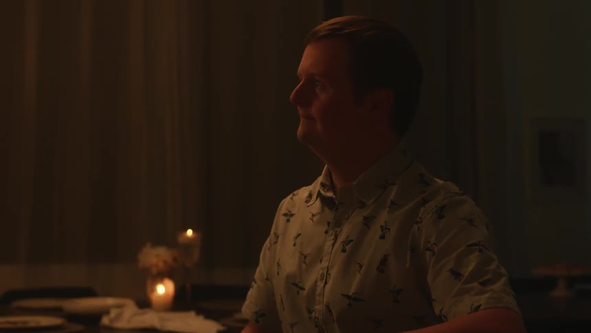 A man sitting at a candle lit table nods his head as he listens and smiles