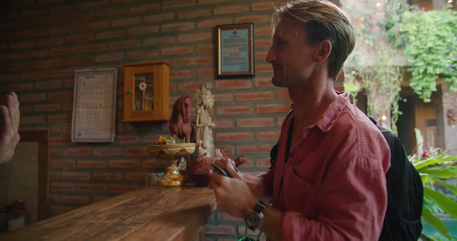 A man standing at a counter thanks an employee as he hands him his credit card