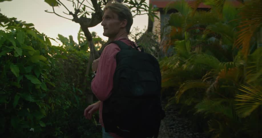 A man walking through a tropical area with a back pack