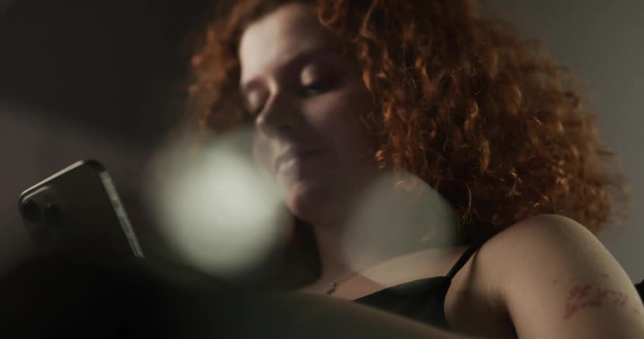 A red headed woman typing on a smartphone