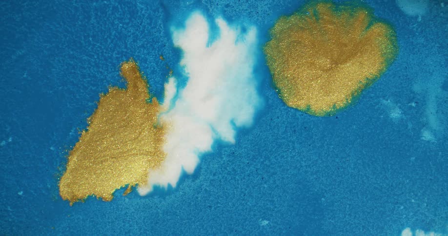 Sparkling gold and white blobs move across a blue liquid substance