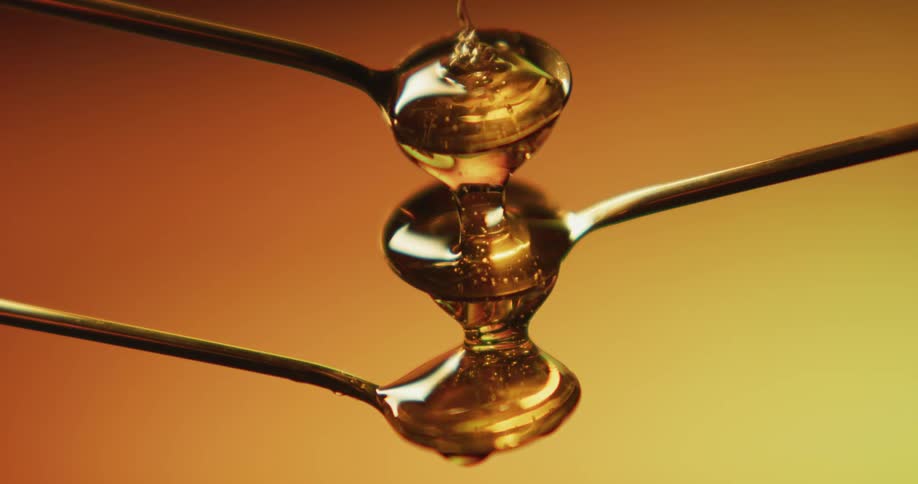 Honey being poured into stacked spoons