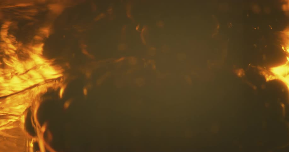 Close up of raspberries floating up a dense amber transparent liquid