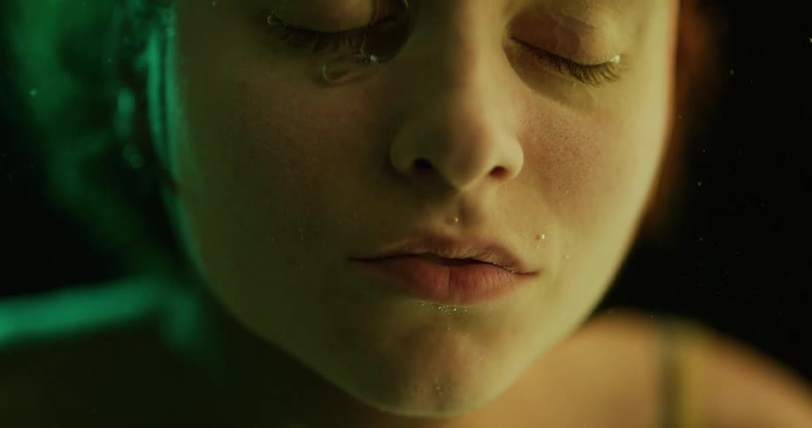 Bubbles floating up from a womans nose as she keeps her face submerged in water