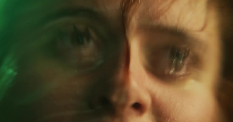 Close up of the eyes of the wet face of a woman dripping water over the surface