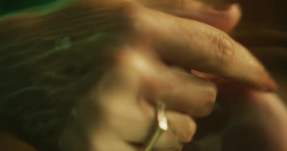 A womans hands slowly rubbing under the surface of water