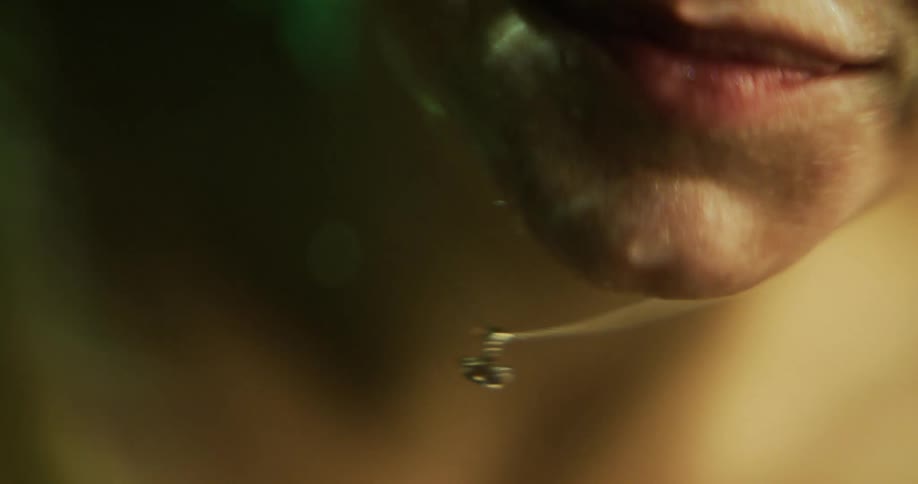 Close up of the face of a wet woman dripping water while talking over the surface